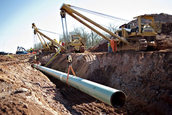 A sixty-foot section of pipe is lowered into a trench during construction of the Gulf Coast Project pipeline in Prague, Oklahoma, U.S., on Monday, March 11, 2013. The Gulf Coast Project, a 485-mile crude oil pipeline being constructed by TransCanada Corp., is part of the Keystone XL Pipeline Project and will run from Cushing, Oklahoma to Nederland, Texas. Photographer: Daniel Acker/Bloomberg via Getty Images